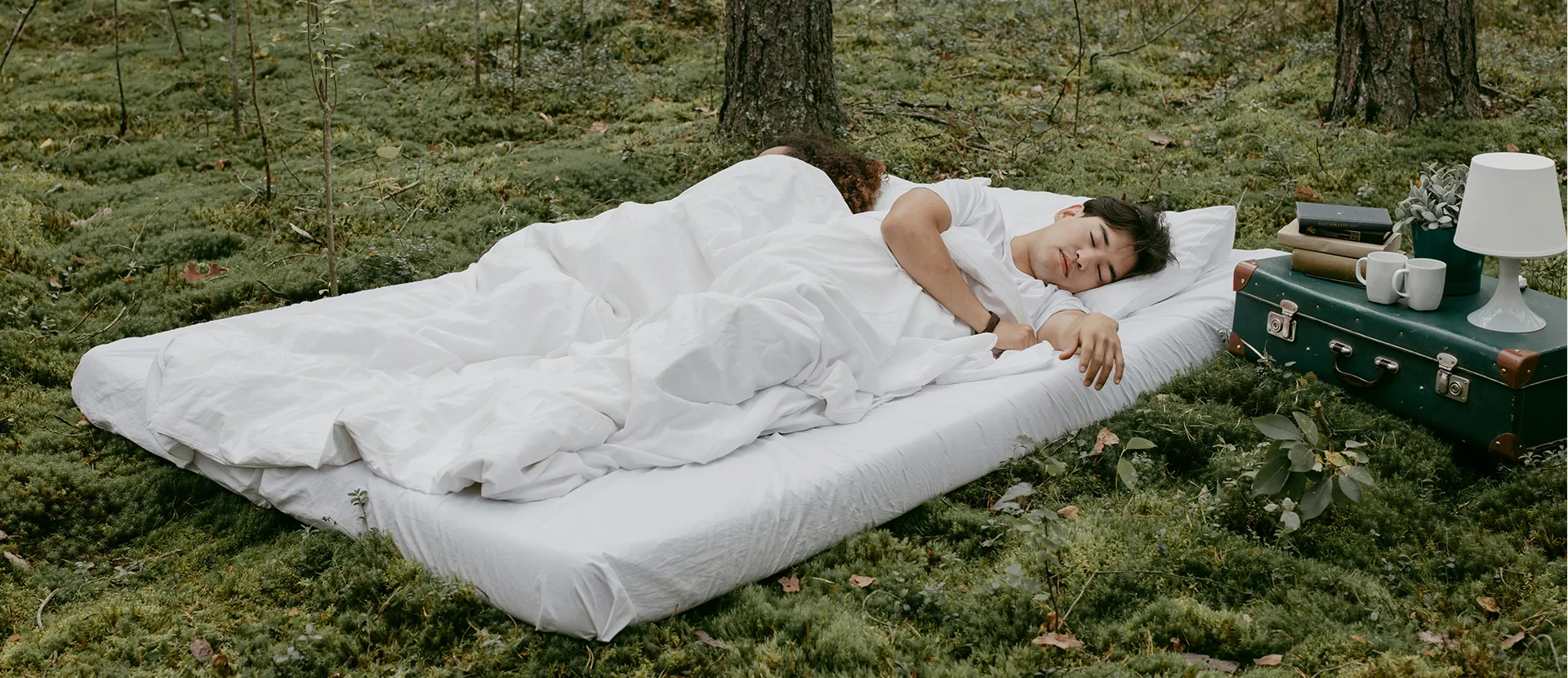 Čovek i žena koji spavaju na dušeku koji je na travi