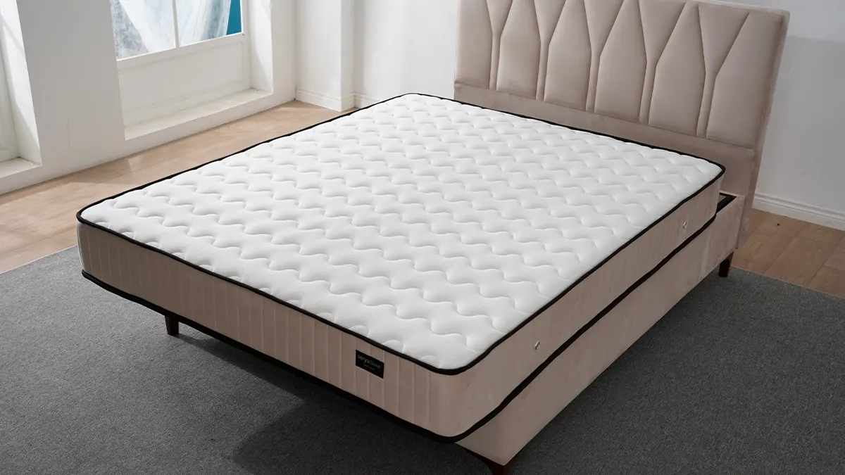 Krevet tapaciranim uzglavljem sa dekorativnim štepom i stabilnim drvenim nogarima na kome je dušek